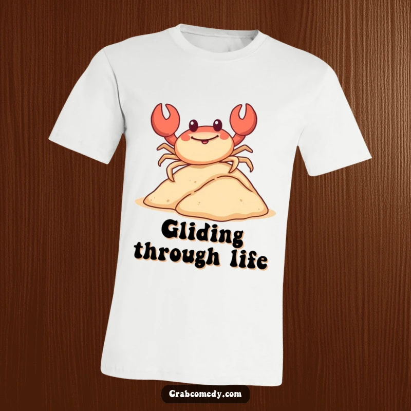 A happy crab is captured mid-slide down a small sand dune on its shell, on a t-shirt.